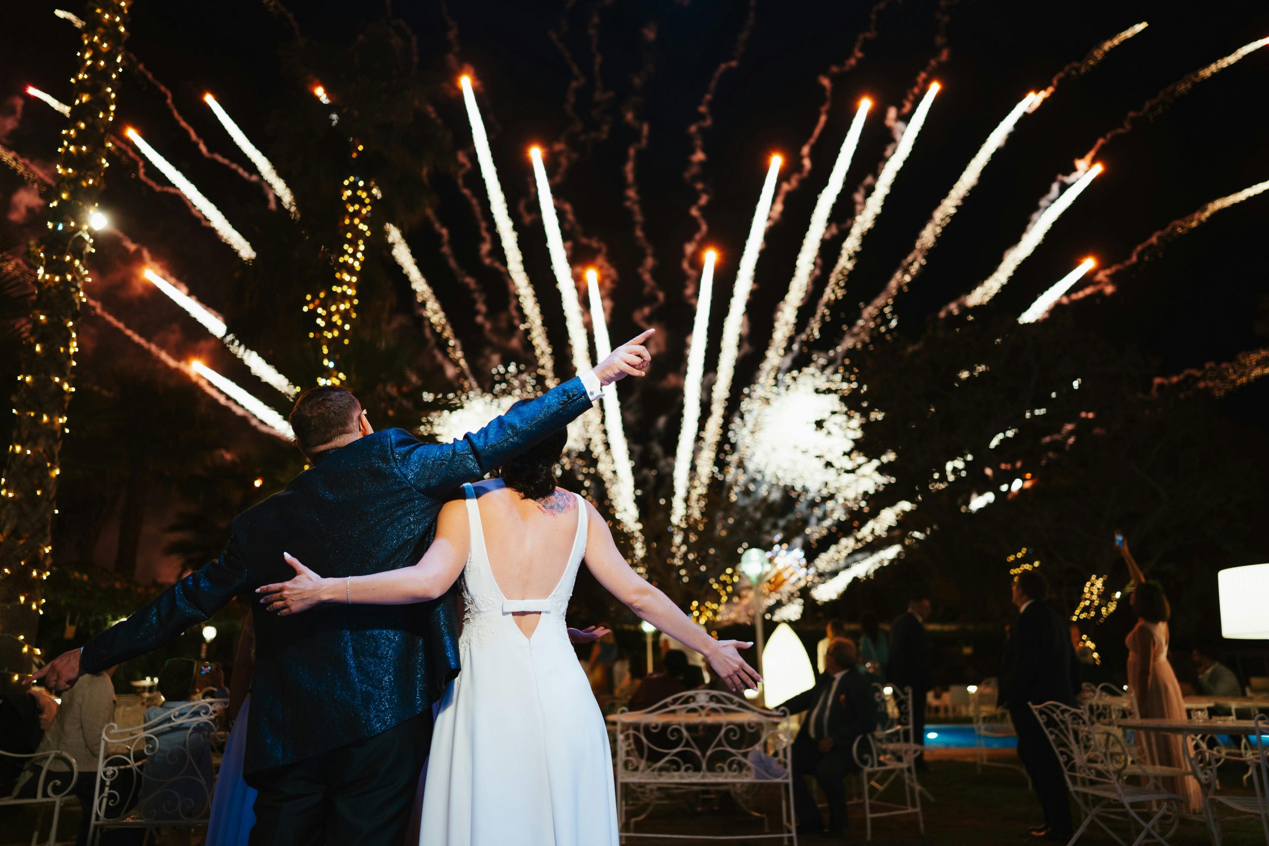 Couple celebrating their wedding night under spectacular fireworks display outdoors.