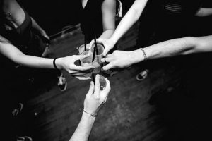 Black and white image of friends celebrating with drinks in a lively setting.